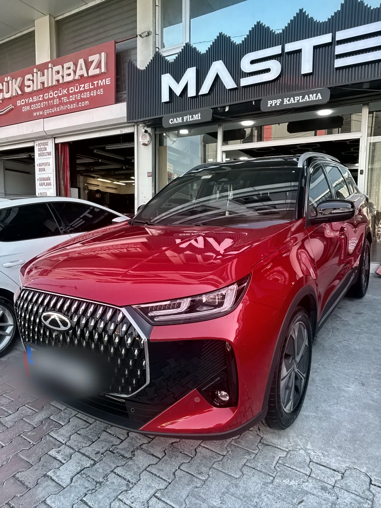 Dükkân önünde PPF kaplamalı kırmızı SUV